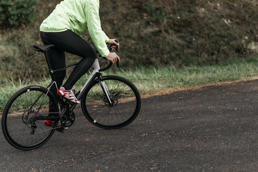 Cyclist on a road bike passing a grassy verge