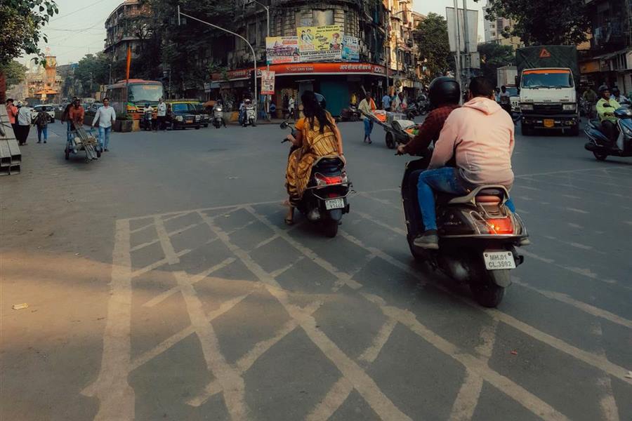 Scooters crossing a Mumbai junction in evening light