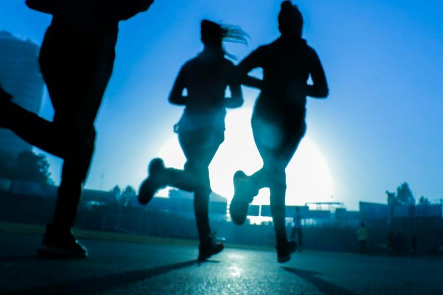 Silhouettes of three runners on a road at dawn